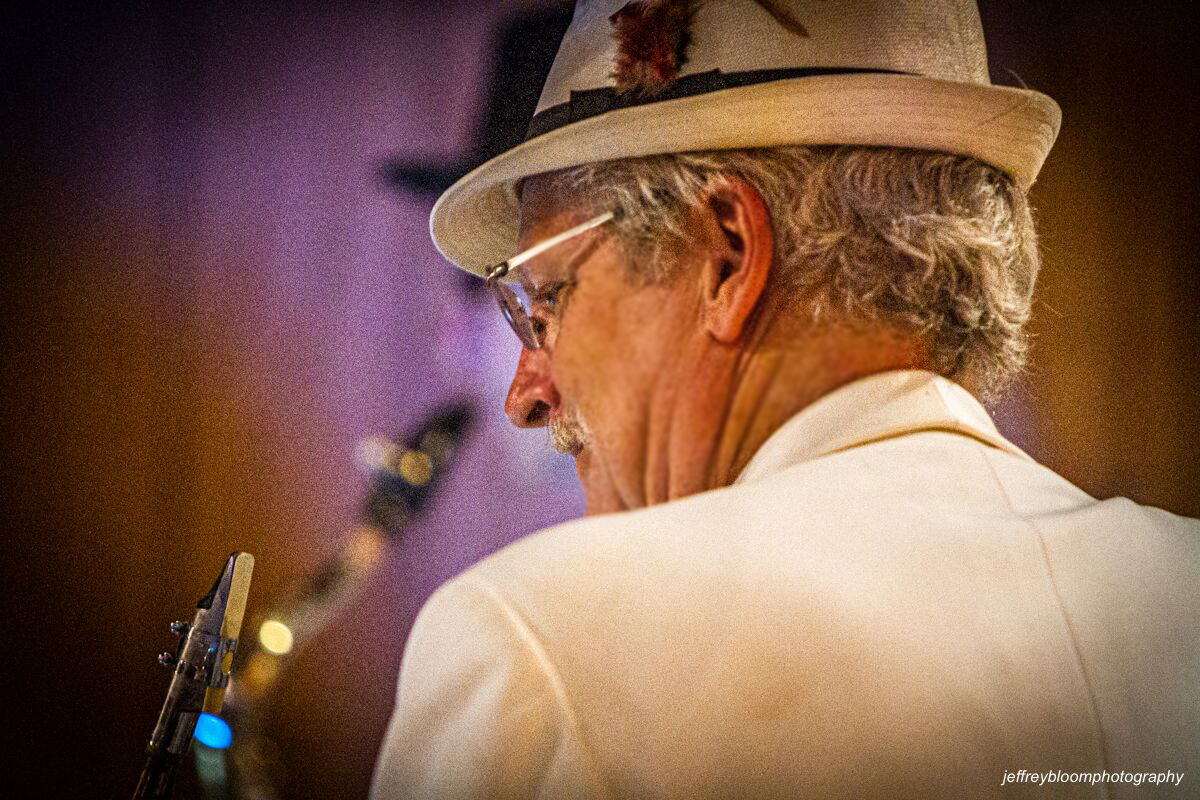 Lead performer kneeling on stage with full band